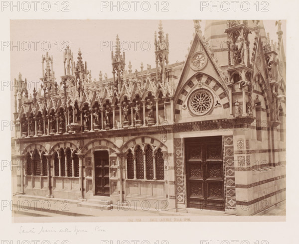 Exterior of the Santa Maria della Spina in Pisa, Italy, Parte Laterale della Spina, Pisa, photograph, number: '1042.', inscription: 'Santa Maria della SPina, Pisa', 1851 - 1900, photographer, Tuscany, pasteboard, paper, albumen print, height 311 mm x width 384 mm, church (exterior), Santa Maria della Spina, A sepia-toned photograph of an ornate stone façade showing a row of pointed arches and slender columns topped by a decorative balustrade with sculpted figures standing within small niches and beneath intricately carved pinnacles, a larger triangular gable with a circular rosette window and striped stone pattern adjacent to a tall carved door with geometric panels, patterned stonework around the doorway, multiple trefoil and lancet window openings with lattice grilles, and a stepped stone pavement in front.