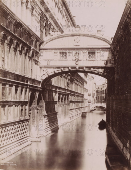 Ponte dei sospiri, Bridge of Sighs in Venice, Italy, Venezia, photograph, number: '9.', Venice, 1851 - 1900, photographer, pasteboard, paper, albumen print, albumendruk, height 369 mm x width 310 mm, canals, waters (in city), bridge, A narrow canal runs between two tall stone buildings with ornate facades, decorative arches, columns, carved reliefs, and patterned masonry; a covered arched bridge spans the canal with sculpted faces along its underside and carved panels and lattice windows on its exterior; a small boat with a pointed bow floats on the calm reflective water near the shadowed side of the right-hand wall; a distant arched bridge and more buildings line the canal further back under soft lighting.
