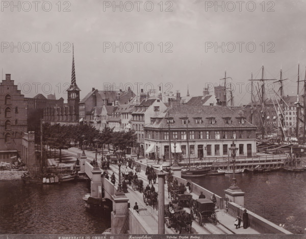 Knippelsbro, View of the Knippelsbro in Copenhagen, Kjøbenhavn og Omegn, photograph, number: '52.', Copenhagen (city), publisher: Vilhelm Trydes, Denmark, 1880 - 1910, photographer, paper, pasteboard, baryta paper, daylight collodion silver print, height 222 mm x width 283 mm, height 349 mm x width 455 mm, bridge in city across river, canal, A wide city scene centered on a stone bridge crowded with people, horse-drawn carriages, and pedestrians, flanked by river water with small boats moored along the quay, a row of multi-story buildings with tiled roofs and dormer windows lining the waterfront, tall masts and rigging of sailing ships rising behind the buildings, a narrow street with trees and lampposts leading into the scene, a distinctive tower with a twisted spire visible among the rooftop silhouettes, and numerous architectural details such as chimneys, windows, shop awnings, and street lamps.