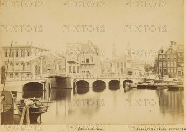 View of a bridge over the Amstel between the two Amstel streets in Amsterdam, Amsterdam, cabinet photograph, annotation: 'Former bridge of the, Amstel - between the two Amstel streets.', publisher: Andries Jager, 1860 - 1890, photographer, paper, pasteboard, albumen print, height 108 mm x width 168 mm, canals, waters (in city), bridge, Amstel (river), A sepia-toned scene shows a canal with calm reflective water and a stone bridge with arched openings spanning across it, a drawbridge section with timber beams and supporting cables visible on the left side of the bridge, small wooden boats moored along the near bank and tied up beside the bridge, a row of multi-story buildings with varied facades and windows lining the far bank, one building with twin towers and a classical portico, another with stepped gables at the right edge, architectural details such as arched windows, balconies, and roof tiles, a small riverside structure near the central buildings, and subtle reflections of the br...