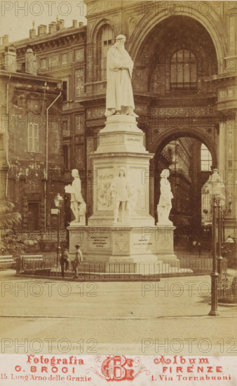 View of the monument to Leonardo da Vinci in Milan, Milano, Monumento a Leonardo da Vinci ..., cabinet photograph, number: '3899', inscription: 'Estese Collezioni, di Vendute d'Italia, d'Égitto e di Palestina, edile in diversi formati., Fotografie di Disegnie Pitture riprodotte dagli originali, grandissimi panorama di un sol pezzo, Grandiosa collezione delle principali, Pitture sistenti nelle Gallerie d'Europa tratta, dalle migliori Stampe', name: 'AC de Roo', address: 'Fotografia Album, G. Brogi Firenze, 15. Lung'Arno delle Grazie 1. Via Tornabuoni', annotation: 'Souvenir de ...', photographer: Giacomo Brogi, Milan, 1864 - 1881, Lombardy, paper, pasteboard, albumen print, height 164 mm x width 106 mm, Person, Leonardo da Vinci, monument, statue, A sepia-toned photograph of a large marble statue on a tall plinth situated in a paved square, the statue depicting a robed standing figure with folded arms atop the pedestal and four smaller sculpted figures positioned around the base; the mo...