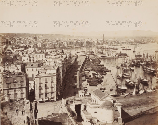 Port et rivière Carmine, View of the port of Naples and the river, Italy, Naples, photograph, inscription: '11.', number: '12', number: 'No. 4005.', inscription: '(+) Sommer', photographer: attributed to Giorgio Sommer, 1857 - 1914, Attributed to, pasteboard, paper, albumen print, albumendruk, height 305 mm x width 405 mm, harbour, city-view in general, 'veduta', A wide aerial view of a coastal city with rows of multi-story buildings lining a long waterfront street, numerous small boats and larger sailing vessels clustered along piers and floating in the harbor, a prominent domed building and other rooftop structures in the foreground, narrow streets between closely set buildings casting long shadows, a tower rising above the distant cityscape, distant low hills on the horizon, and calm water reflecting masts and hulls.