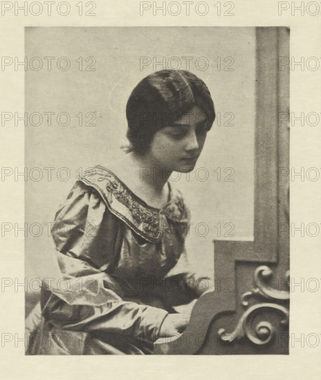 Portrait of an unknown woman as Saint Cecilia, Sainte Cécile, photomechanical print, photographer: Adolphe Gayne de Meyer, cliché maker: Fillon & Heuse, printer (person): Charles Wittmann, Paris, c. 1891 - in or before 1896, printer (person), paper, photoaquatint, height 158 mm x width 127 mm, historical persons not known by name - BB - woman, the virgin martyr Cecilia of Rome, possible attributes: falcon, musical instruments, organ, wreath of roses and lilies, A monochrome image of a young woman shown from the waist up, seated and facing slightly right with her head inclined downward, wearing a dress with a decorated collar and puffed sleeves, her hair parted in the middle and styled close to her head, a faint circular halo-like outline appears above her head, and the right side of the image shows a portion of a carved wooden structure with scrollwork near where her hands rest.