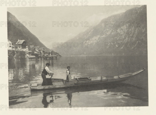 Boat on the Hallstätter See, Lac de Hallstatt, photomechanical print, photographer: Albert baron de Rothschild, Hallstatt, cliché maker: Jacob Blechinger, printer (person): Charles Wittmann, Paris, c. 1891 - in or before 1896, printer (person), Upper Austria, paper, photoaquatint, height 112 mm x width 156 mm, lake, mountains, rowing facing forward, pushing, Hallstätter See, A wide, calm lake bordered by steep, forested mountains fills the scene, with a cluster of lakeside buildings and boathouses along the shore at the left. Two small wooden boats float near the foreground, one with a person standing and another person leaning forward holding an oar; their reflections appear in the water. The overall image is monochrome with soft contrasts and a misty atmosphere over the distant mountains.
