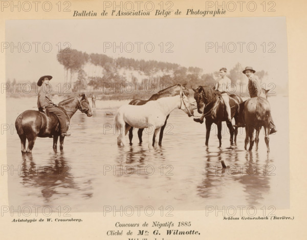 Riders in a river, photograph, page, inscription: 'Concours de Négatifs 1885, Médaille de bronze.', photographer: Georges Wilmotte, printer (person): Wilhelm Cronenberg, Grönenbach, c. 1880 - in or before 1885, printer (person), Bavaria, paper, pasteboard, baryta paper, daylight collodion silver print, height 104 mm x width 154 mm, Photo on unnumbered page., horse, riding a horse, ass, or mule, rider, horseman, river, A sepia photograph shows several people on horseback standing in shallow water with reflections on the surface; one person on the left wears a wide-brimmed hat and loose clothing while sitting on a dark horse, a shirtless rider sits on a dark horse near the center, another person in a hat and jacket sits on a horse to the right, and a light-colored horse and a dark horse stand together between them; trees and distant buildings form a blurred background across the horizon above the group.