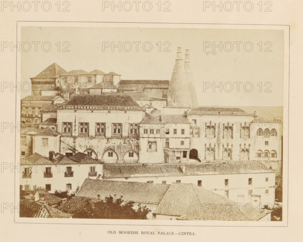 Old Moorish Royal Palace - Cintra, View of the Palace of Sintra, photograph, page, Sintra, c. 1865 - in or before 1870, photographer, paper, albumen print, height 144 mm x width 198 mm, Photo on second unnumbered page after page 30., palace, Palace of Sintra, A sepia-toned photograph showing a cluster of connected historic buildings with tiled roofs and textured facades, featuring arched ground-level openings and rectangular windows with decorative frames, an array of rooftops in the foreground leading back to larger structures, one building with two tall conical chimneys rising above the roofs, several ornate window surrounds and carved stone details on one façade, varied rooflines including sloped and hipped roofs, patches of weathering and discoloration on walls, and a plain sky above.