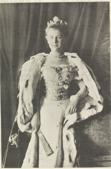 Portrait of Wilhelmina, Queen of the Netherlands, photomechanical print, Portrait of Wilhelmina wearing an ermine cloak. In her right hand a fan. In the lower margin her name and title., photographer: Richard Kameke, cliché maker: Emrik & Binger, Haarlem, 1897, paper, collotype, photogravure, height 273 mm x width 186 mm, The title mentioned here refers to the highest title obtained by the sitter, not necessarily to the title the sitter bears in this image., Person, Wilhelmina of the Netherlands, A black and white portrait of a woman standing against a draped curtain, wearing a decorated bodice and a long skirt, with a fur-lined cloak draped over her shoulders. She has a small floral crown on her hair and a short necklace around her neck. One hand rests on the cloak near her waist while the other holds a fan that hangs down in front of her skirt. The cloak shows visible furry texture and darker spots, and a patterned chair or cushion is partially visible near her side. The overall imag...
