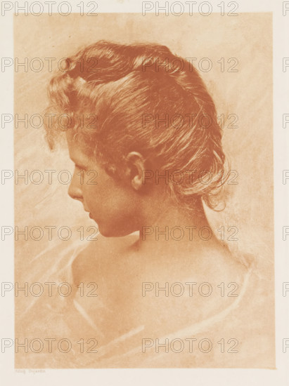 Primavera, Portrait of an unknown woman, page, photomechanical print, photographer: Robert Demachy, cliché maker: Paul Dujardin, 1896, paper, photoaquatint, height 209 mm x width 152 mm, adult woman, the graphic arts, A sepia-toned portrait of a young person shown in profile facing left, with short wavy hair swept back from the forehead and soft curls near the nape, a smooth neck and bare shoulders partially draped with a translucent, flowing fabric, set against a plain textured background.