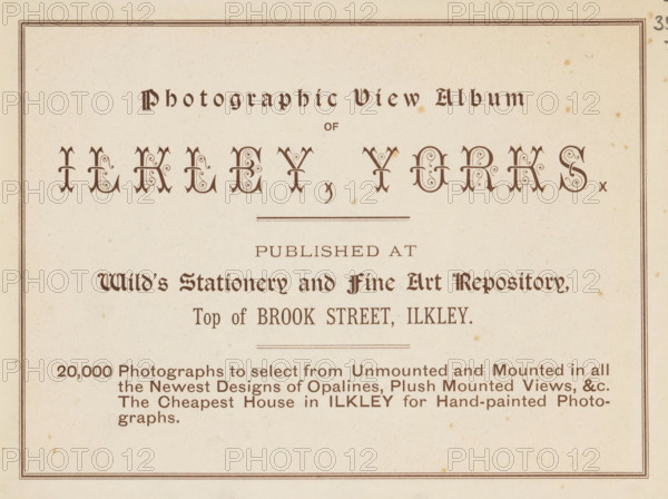 Photographic view album of Ilkley, Yorks, book, inscription: 'ex libris SFJ', publisher: Wild's Stationery and Fine Art Repository, Ilkley, c. 1900, Wild's Stationery and Fine Art Repository, Yorkshire, textile materials, pasteboard, paper, linen (material), printing, collotype, height 157 mm x width 201 mm x thickness 4 mm, A cream colored page with a double-lined rectangular border containing decorative dark brown ornamental headings and stylized lettering, ornate drop-cap style characters arranged near the top, thin horizontal rule lines, a block of smaller dark brown serif text lines in the middle and lower areas, and scattered small brown speckles and age spots across the paper.