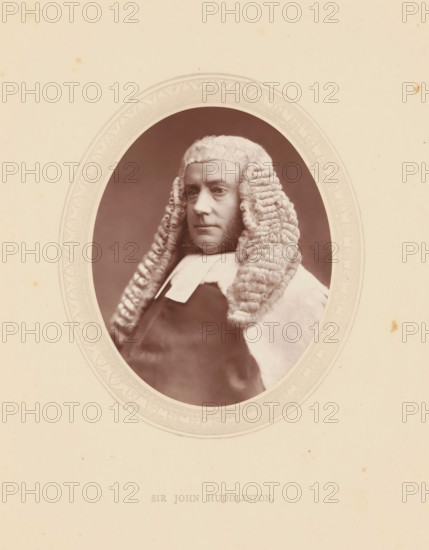 Sir John Huddleston, page, photomechanical print, photographer: Lock & Whitfield, cliché maker: anonymous, c. 1871 - in or before 1876, paper, Woodburytype, height 115 mm x width 89 mm, Person, John Walter Huddleston, magistracy, judges, wig, historical persons (portraits and scenes from the life) ((full) bust portrait), A sepia portrait of a person wearing a full, curled judicial wig and a dark robe with a white collar, shown inside an ornate oval frame on a light, slightly speckled background.