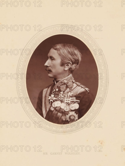 Sir Garnet Wolseley, page, photomechanical print, photographer: Lock & Whitfield, cliché maker: anonymous, c. 1871 - in or before 1876, paper, Woodburytype, Woodburytypie, height 115 mm x width 89 mm, Person, Garnet Wolseley, officer, historical persons (portraits and scenes from the life) ((full) bust portrait), An oval sepia portrait of a man in profile set against a plain light background, the man wearing a dark formal uniform with braided shoulder detail and a high collar, a neatly groomed mustache and short hair combed back, multiple medals and star-shaped decorations pinned across his chest and suspended from ribbons, the portrait framed by an ornate oval border with decorative patterns, the surrounding paper showing a few small aged spots.