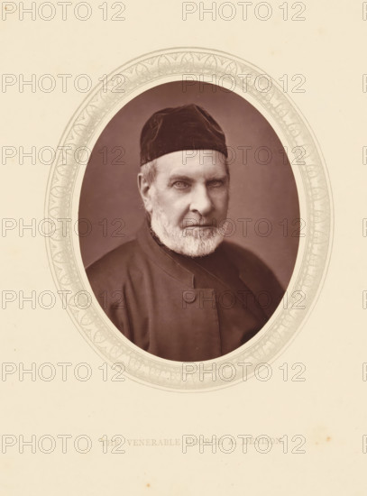 Lord Redesdale, page, photomechanical print, photographer: Lock & Whitfield, cliché maker: anonymous, c. 1871 - in or before 1876, paper, Woodburytype, Woodbury Process, height 115 mm x width 89 mm, Person, George Denison, functions and dignitaries, episcopal Protestant churches, historical persons (portraits and scenes from the life) ((full) bust portrait), An oval portrait of an older man with a trimmed white beard and light-colored eyes wearing a dark cap and a dark buttoned garment, set against a dark background and surrounded by an ornate decorative oval frame on a light-colored sheet.