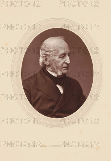The right hon. Spencer Horatio Walpole, page, photomechanical print, photographer: Lock & Whitfield, cliché maker: anonymous, c. 1871 - in or before 1876, paper, Woodburytype, height 115 mm x width 89 mm, Person, Spencer Horatio Walpole, politician, eg party leader, historical persons (portraits and scenes from the life) ((full) bust portrait), An oval sepia-toned portrait of an older man shown in three-quarter profile facing right, framed by an ornate decorative border, with the man wearing a dark suit jacket, waistcoat, and bow tie, his hair swept back and sideburns visible, set against a plain darker background and surrounded by a light beige mat with subtle spots and marks.