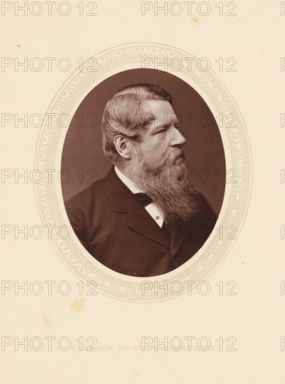 Right hon. Sir Stafford Northcote, page, photomechanical print, photographer: Lock & Whitfield, cliché maker: anonymous, c. 1871 - in or before 1876, paper, Woodburytype, Woodbury Process, height 115 mm x width 89 mm, Person, Stafford Northcote, politician, eg party leader, historical persons (portraits and scenes from the life) ((full) bust portrait), An oval photographic portrait of a man in profile set against a decorated oval frame on a pale background, showing a middle-aged man with neatly combed hair and a full long beard, wearing a dark suit jacket, a white shirt collar, and a bow tie, the portrait area having a darker background and the surrounding page showing faint spots and subtle decorative border patterns.