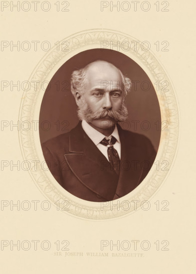 Sir Joseph William Bazalgette, page, photomechanical print, photographer: Lock & Whitfield, cliché maker: anonymous, c. 1871 - in or before 1876, paper, Woodburytype, Woodbury Process, height 115 mm x width 89 mm, Person, Joseph Bazalgette, engineering, historical persons (portraits and scenes from the life) ((full) bust portrait), A sepia-toned oval portrait set within a decorative oval border shows a middle-aged man with a receding hairline and bushy sideburns that connect to a thick mustache, wearing a dark suit jacket with a visible lapel, a white collared shirt, and a patterned tie; his expression is neutral and he faces forward against a plain dark background, with the surrounding paper showing subtle discoloration and a pale background.