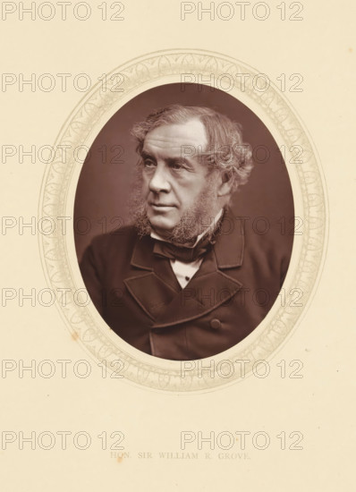 Hon. Sir William R. Grove, page, photomechanical print, photographer: Lock & Whitfield, cliché maker: anonymous, c. 1871 - in or before 1876, paper, Woodburytype, Woodbury Process, height 115 mm x width 89 mm, Person, William Grove, magistracy, judges, historical persons (portraits and scenes from the life) ((full) bust portrait), A sepia-toned oval portrait of an older man with wavy hair and heavy sideburns set against a dark background, framed by an ornate decorative oval border on a light cream paper. The man is shown from the chest up wearing a dark suit jacket with wide lapels, a high-collared shirt, and a bow tied at the neck. His gaze is directed slightly to the side, and his facial expression is neutral. The surrounding paper shows faint aging marks and small spots.