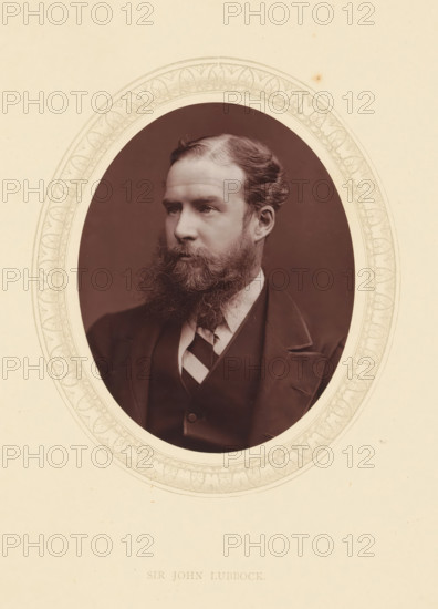 Sir John Lubbock, page, photomechanical print, photographer: Lock & Whitfield, cliché maker: anonymous, c. 1871 - in or before 1876, paper, Woodburytype, Woodbury Process, height 115 mm x width 89 mm, Person, John Lubbock, banker, historical persons (portraits and scenes from the life) ((full) bust portrait), An oval sepia portrait of a bearded man in a suit is centered on a cream-colored background with a decorative oval border; the man is shown from the chest up, facing slightly to the viewer's left, with neatly combed hair and a full, bushy beard, wearing a dark jacket, waistcoat, collared shirt, and a diagonally striped tie, and framed by a patterned inner rim against a plain outer margin.