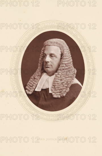 Lord justice Brett, page, photomechanical print, photographer: Lock & Whitfield, cliché maker: anonymous, c. 1871 - in or before 1876, paper, Woodburytype, Woodbury Process, height 115 mm x width 89 mm, Person, William Brett, lawyer, attorney at law, historical persons (portraits and scenes from the life) ((full) bust portrait), An oval portrait of a man wearing a full curled judicial wig and dark robe with a white neckband, shown from the chest up against a dark background and framed by a decorative oval border on a pale page.