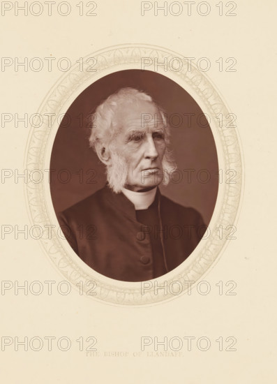 The bishop of Llandaff, page, photomechanical print, photographer: Lock & Whitfield, cliché maker: anonymous, c. 1873 - in or before 1878, paper, Woodburytype, Woodbury Process, height 115 mm x width 89 mm, Person, Alfred Ollivant, archbishop, bishop, etc. (Roman Catholic), historical persons (portraits and scenes from the life) ((full) bust portrait), A sepia-toned oval portrait of an elderly man with pale hair and long sideburns, shown from the chest up, wearing a dark clerical garment with a high white collar and buttons, his face turned slightly to the side with a serious expression, set within a decorative patterned oval border on a light background.