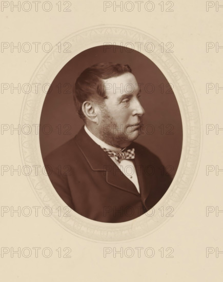 Right hon. Sir George Jessel, page, photomechanical print, photographer: Lock & Whitfield, cliché maker: anonymous, c. 1876 - in or before 1881, paper, Woodburytype, Woodbury Process, height 115 mm x width 89 mm, Person, George Jessel, magistracy, judges, historical persons (portraits and scenes from the life) ((full) bust portrait), A sepia-toned oval portrait of a man shown in profile facing right, with short dark hair and mutton chop sideburns, wearing a dark jacket with a notched lapel, a light shirt, and a patterned bow tie, set against a plain dark background and framed by an ornate pale oval mat with decorative border, all on a pale cream background.