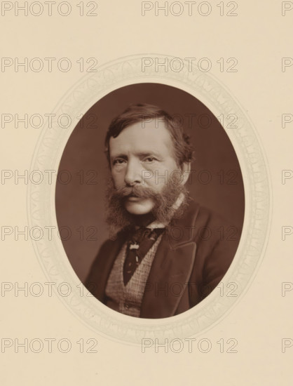 William Charles T. Dobson, page, photomechanical print, photographer: Lock & Whitfield, cliché maker: anonymous, c. 1876 - in or before 1881, paper, Woodburytype, Woodbury Process, height 115 mm x width 89 mm, Person, William Charles Thomas Dobson, portrait, self-portrait of painter, historical persons (portraits and scenes from the life) ((full) bust portrait), A sepia portrait of a man shown within an ornate oval frame against a light beige background, the man has a full styled beard and prominent sideburns, short neatly combed hair, and a solemn facial expression; he wears a dark jacket with a visible lapel, a patterned waistcoat, and a necktie with a decorative knot, and the oval mat around the portrait has a faint decorative leaf-and-scroll border.
