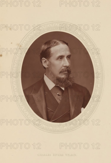 Charles Rivers Wilson, page, photomechanical print, photographer: Lock & Whitfield, cliché maker: anonymous, c. 1876 - in or before 1881, paper, Woodburytype, Woodbury Process, height 115 mm x width 89 mm, Person, official, civil servant, historical persons (portraits and scenes from the life) ((full) bust portrait), A sepia-toned oval portrait of a man with neatly combed hair and a full beard, shown from the chest up and turned slightly to the side, wearing a dark suit with a high-collared shirt and a waistcoat, set against a plain dark background and surrounded by an ornate patterned oval border on a light-colored mat.
