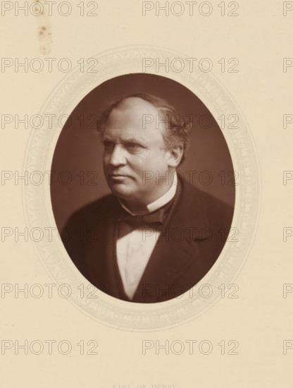 Earl of Derby, page, photomechanical print, photographer: Lock & Whitfield, cliché maker: anonymous, c. 1876 - in or before 1881, paper, Woodburytype, Woodbury Process, height 115 mm x width 89 mm, Person, Edward Henry Stanley (15th Earl of Derby), politician, eg party leader, historical persons (portraits and scenes from the life) ((full) bust portrait), An oval sepia portrait of a middle-aged man with a rounded face and receding hairline, wearing a dark jacket, a white shirt, and a bow tie, set against a plain darker background and mounted on a light-colored card with a faint decorative oval border.