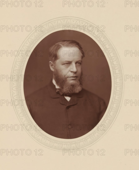 Sir Henry Charles Lopes, page, photomechanical print, photographer: Lock & Whitfield, cliché maker: anonymous, c. 1876 - in or before 1881, paper, Woodburytype, Woodbury Process, height 115 mm x width 89 mm, Person, Henry Lopes, magistracy, judges, historical persons (portraits and scenes from the life) ((full) bust portrait), A sepia-toned oval portrait of a middle-aged man with a full beard and short hair, shown from the chest up and turned slightly to his left, wearing a dark coat with a high collar and a visible bow at the neck, set against a dark background and framed by a decorative oval mat with a patterned inner border on a light background.