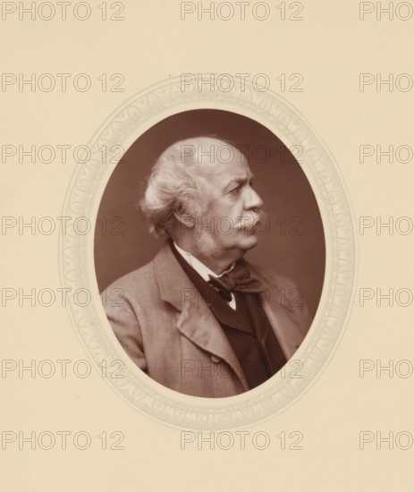 Sir Henry Creswicke Rawlinson, page, photomechanical print, photographer: Lock & Whitfield, cliché maker: anonymous, c. 1877 - in or before 1882, paper, Woodburytype, Woodbury Process, height 115 mm x width 89 mm, Person, Henry Rawlinson, scholar, philosopher, historical persons (portraits and scenes from the life) ((full) bust portrait), A sepia-toned oval portrait of an older man shown in profile facing right, with a receding hairline and wavy white hair at the sides, prominent sideburns and a thick moustache, wearing a jacket over a vest and a bow tied at the collar; the oval image is set within a decorative light-colored frame with a patterned border against a plain light background.