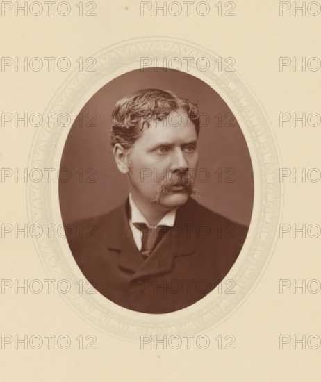 Marcus Stone, page, photomechanical print, photographer: Lock & Whitfield, cliché maker: anonymous, c. 1877 - in or before 1882, paper, Woodburytype, Woodbury Process, height 115 mm x width 89 mm, Person, portrait, self-portrait of painter, historical persons (portraits and scenes from the life) ((full) bust portrait), An oval sepia photograph of a man with wavy hair and a prominent mustache is centered on a pale background, the man shown from the chest up wearing a dark jacket, high collared shirt, and tie, his gaze directed slightly to the side, and the oval photo is bordered by a faint decorative pattern on the surrounding mat.