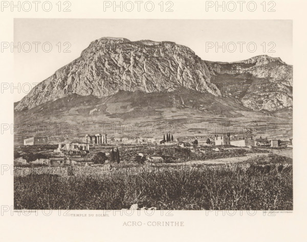 Acro-Corinth, View of the Acrokorinthos, page, photomechanical print, inscription: 'Temple du soleil', Pelopónnesos, cliché maker: Dujardin, printer (person): Chardon-Wittmann, c. 1880 - in or before 1890, photographer, printer (person), paper, photoaquatint, height 146 mm x width 213 mm, landscape with ruins, mountains, Akrokorinthos, A large rocky mountain dominates the upper portion of the image with steep textured cliffs and a flatter ridge along its top, lighter sky above, and a gently sloping plains area below showing patches of vegetation and rocky ground; scattered in the midground are small stone ruins and buildings with vertical column remnants and taller slender trees nearby, while the foreground shows dense grasses and low shrubs with a rough stone wall along the lower edge.