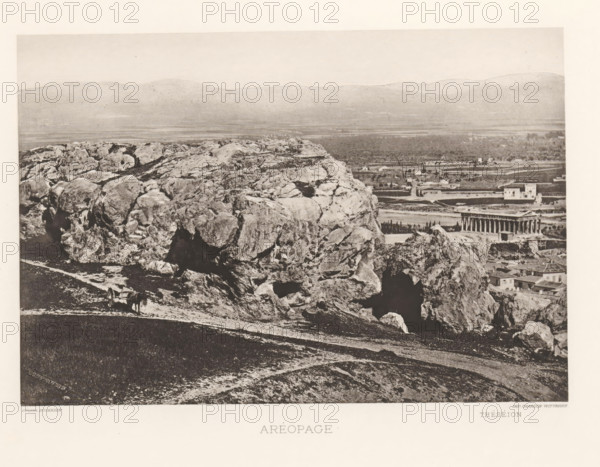 Aréopage, View of the Areopagus in Athens, page, photomechanical print, inscription: 'Théséion', Athens, cliché maker: Dujardin, printer (person): Chardon-Wittmann, c. 1880 - in or before 1890, photographer, printer (person), Athene, Periféreia Protevoúsis, paper, photoaquatint, height 145 mm x width 215 mm, landscape with ruins, (high) hill, court session (court of justice), Areopagus, A wide panoramic scene showing a rocky hillside in the foreground with large rough boulders and exposed rock faces, a dirt path running along the slope, and a simple cart with an animal standing beside it; beyond the rocks a flat plain stretches toward distant low hills, and near the middle right a classical temple with a rectangular colonnaded structure sits among scattered buildings and trees.