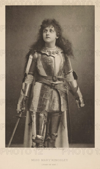 Miss Mary Kingsley (Joan of Arc), page, photomechanical print, photographer: Downey, William & Daniel, cliché maker: anonymous, publisher: Virtue & Co., London, c. 1880 - in or before 1890, paper, photoaquatint, height 197 mm x width 123 mm, Person, Mary Kingsley, portrait of actor, actress, A sepia-toned portrait of a person wearing a full suit of metal armor, including a breastplate with decorative elements at the neckline, articulated shoulder and arm pieces, gauntlets, a belted waist with metal plates over a chainmail apron, and greaves over the legs; the person has long, curly hair and is looking upward and slightly to the side with a neutral facial expression, one hand resting near the hilt of a sword and the other hanging by the side, the background is plain and darker than the subject, and the image has a lighter border around it.