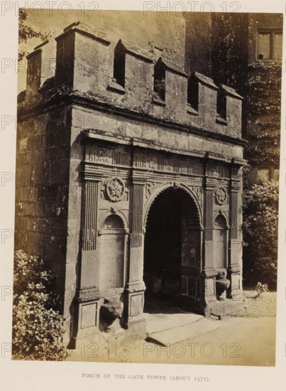 Gate of a tower of Kenilworth Castle, Porch of the Gate Tower (about 1571), photograph, page, Kenilworth Castle, c. 1862 - in or before 1872, photographer, Kenilworth, paper, albumen print, height 203 mm x width 152 mm, ruin of a dwelling, house, castle, monumental door, porch, 'aediculum', A sepia photograph of a stone gate porch showing an arched entrance flanked by decorated pilasters and recessed niches, above which runs a horizontal entablature with carved panels and circular floral medallions; the upper section features a crenellated parapet with rectangular embrasures, and the stone surfaces show weathering and patches of lichen; foliage is visible at the sides of the structure and a shadowed interior beyond the arch contrasts with the sunlit stone step and ground in front.