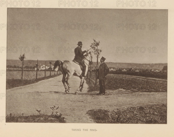 Man riding a horse and presumably participating in ring jousting, Taking the ring, page, photomechanical print, cliché maker: Römmler & Jonas, Dresden, c. 1879 - in or before 1889, photographer, paper, collotype, photogravure, height 100 mm x width 140 mm, horse, riding a horse, ass, or mule, rider, horseman, head-gear: bowler hat, A sepia-toned photograph showing a person seated on a light-colored horse on a road, the rider wearing a hat and leaning slightly forward while holding the reins, facing another standing person who is dressed in a dark suit and hat and holding a long pole or stick near a small tree, a line of small trees and a distant low horizon with scattered buildings visible in the background, with the foreground showing a textured dirt or gravel surface and some low vegetation.
