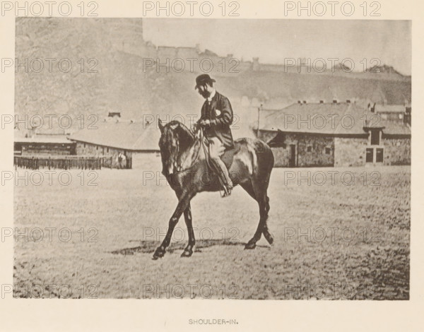 Man on a horse in dressage, Shoulder-in, page, photomechanical print, photographer: Alexander Nicol (possibly), Edinburgh (possibly), cliché maker: Römmler & Jonas, Dresden, c. 1879 - in or before 1889, paper, collotype, photoprint, height 97 mm x width 137 mm, horse, riding a horse, ass, or mule, rider, horseman, head-gear: bowler hat, A sepia-toned photograph showing a person wearing a hat and jacket riding a horse across an open grassy area with several low stone buildings and a fence in the background, the rider seated upright and holding the reins while the horse walks with its head lowered.