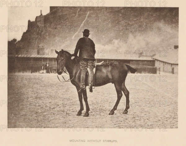 Mounting without Stirrups, Man mounting a horse without using the stirrups, page, photomechanical print, cliché maker: Römmler & Jonas, Dresden, c. 1879 - in or before 1889, photographer, paper, collotype, photoprint, height 97 mm x width 137 mm, horse, riding a horse, ass, or mule, rider, horseman, head-gear: bowler hat, A sepia-toned photograph shows a person wearing a dark coat and a rounded hat sitting on a dark horse viewed from behind, with one hand resting on the horse's neck and legs visible without stirrups, the horse standing on a textured ground in front of a distant low building and a steep cliff rising behind it, with a hazy sky above.