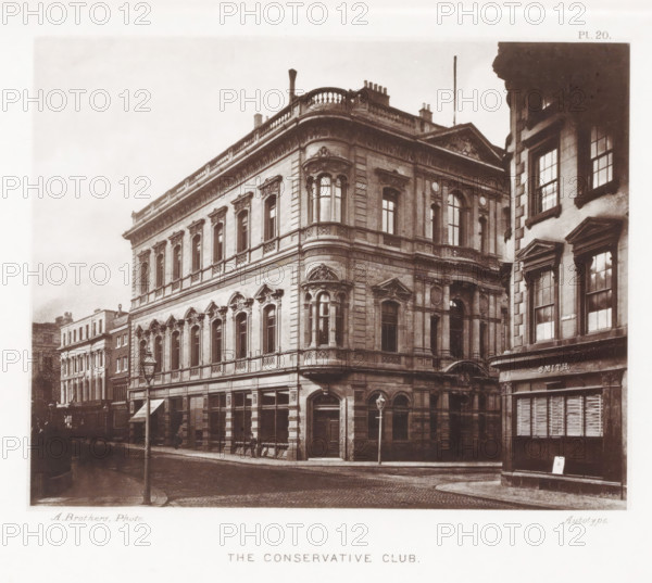 The Conservative Club, Façade of the Conservative Club in Manchester, page, photomechanical print, number: 'Pl. 20.', photographer: Brothers, Alfred, Manchester, cliché maker: anonymous, c. 1868 - in or before 1878, printer (person), paper, collotype, photoprint, height 145 mm x width 183 mm, façade (of house or building), A sepia-toned photograph of a street corner featuring a large ornate stone building with multiple stories, decorative window frames, balconies with balustrades, and sculpted architectural details around arched and rectangular windows; a rounded corner section with bay windows rises above the corner entrance, and a lamppost stands on the cobbled road in front; adjacent buildings with tall windows and pedimented window surrounds are visible to the right and along the street, and a shopfront with a shuttered window appears at street level.