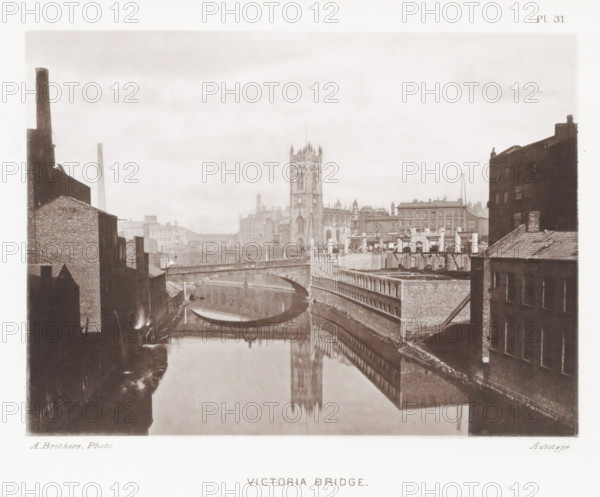 Victoria Bridge, View of the Victoria Bridge over the Irwell in Manchester, page, photomechanical print, number: 'Pl. 31.', photographer: Brothers, Alfred, Manchester, cliché maker: anonymous, c. 1868 - in or before 1878, printer (person), paper, collotype, photoprint, height 138 mm x width 188 mm, Print after page 30., bridge in city across river, canal, tower, clock tower, monumental adornment, A sepia-toned cityscape showing a river flanked by brick buildings with a stone bridge arching across the water and reflecting in the river, industrial chimneys and rooftops visible on either side, a tall Gothic church tower rising in the center background with its reflection mirrored in the water, and rows of buildings and architectural details lining the riverbank under an overcast sky.