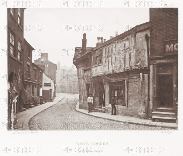 Poet's Corner, Long Millgate, View of Poet's Corner in Manchester, page, photomechanical print, number: 'Pl. 35.', photographer: Brothers, Alfred, Manchester, cliché maker: anonymous, c. 1868 - in or before 1878, printer (person), paper, collotype, photoprint, height 131 mm x width 183 mm, street, A narrow cobbled street curves between rows of old brick and timber buildings with visible wear and weathering; the building on the right projects over the pavement with exposed timbers, peeling plaster, a slanted tiled roof, and several chimney pots, while the left side shows multi-storey brick facades with windows and awnings and stacked chairs along the pavement; two men stand near the projecting building—one facing the camera and one looking into a shop window that displays small objects and fabric, and nearby a tall pole leans against the wall; further down the street more brick buildings and chimneys recede into a misty distance.