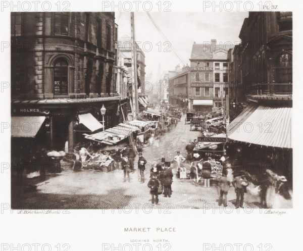 View of Market Place in Manchester, Market Place, looking north, page, photomechanical print, number: 'Pl. 37.', photographer: Brothers, Alfred, Manchester, cliché maker: anonymous, c. 1868 - in or before 1878, printer (person), paper, collotype, photoprint, height 135 mm x width 192 mm, Print after page 32., market, four-wheeled, animal-drawn vehicle, eg: cab, carriage, coach, A busy street scene viewed from above shows rows of multi-story stone and brick buildings lining a narrow cobbled roadway, with awnings and market stalls extending out from the shopfronts and many goods displayed on tables and in crates. People in period dress stand, walk, and browse among the stalls, some appearing blurred by motion, while a few men stand more clearly in the foreground. Horse-drawn carts and carriages are visible along the street amid clusters of pedestrians, and tall shop façades with windows and decorative architectural details rise on both sides. A tall wooden pole with wires runs up near th...