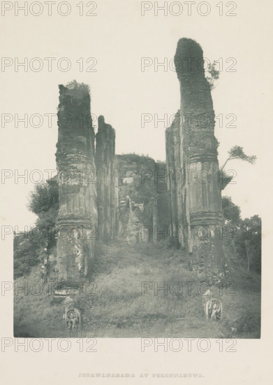 Ruins of the Lankatilaka Vihara at Polonnaruwa, Sri Lanka, page, photomechanical print, title: 'JETAWANARAMA AT POLONNARUWA', photographer: Henry William Cave, Polonnaruwa, cliché maker: anonymous, 1896, South Asia, paper, Woodburygravure, height 196 mm x width 146 mm, Print for page 109., temple, shrine, Hinduism, Buddhism, Jainism, ruin of a building, architecture, A tall stone ruin rises from a grassy slope, consisting of several weathered vertical pillars and walls with layered textures and eroded surfaces, some topped with patches of vegetation and small trees; two sculpted stone figures sit near the base of the slope facing forward, and bushes and foliage grow around the lower parts of the structure, all shown against a pale, empty sky.