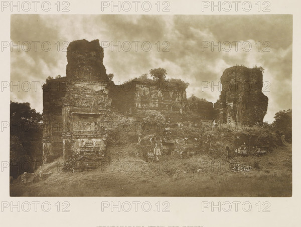 Ruins of the Lankatilaka Vihara at Polonnaruwa, Sri Lanka, page, photomechanical print, title: 'JETAWANARAMA (FROM THE NORTH).', photographer: Henry William Cave, Polonnaruwa, cliché maker: anonymous, 1896, South Asia, paper, Woodburygravure, height 126 mm x width 195 mm, Print for page 111., temple, shrine, Hinduism, Buddhism, Jainism, ruin of a building, architecture, A sepia-toned photograph showing a large ruined stone structure with weathered walls and crumbling towers rising against a cloudy sky, vegetation and small trees growing on and around the masonry, carved stone details and niches visible on the facade, grassy ground in front with scattered stones and low plants, and dense foliage at the edges of the composition.
