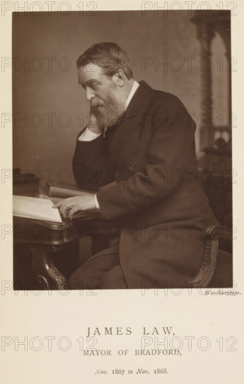 Portrait of James Law, James Law, mayor of Bradford, page, photomechanical print, inscription: 'Nov. 1867 to Nov. 1868.', photographer: Appleton & Co., Bradford (England), cliché maker: anonymous, c. 1871 - in or before 1881, paper, Woodburytype, Woodburytypepie, height 116 mm x width 92 mm, historical persons (portraits and scenes from the life) ((full) bust portrait), A seated older man with a full beard and short hair leans his head on one hand while resting his other hand on an open book on a table, wearing a dark suit with visible cuffs and seated on an ornately carved chair, with a blurred background and a neutral-toned backdrop.