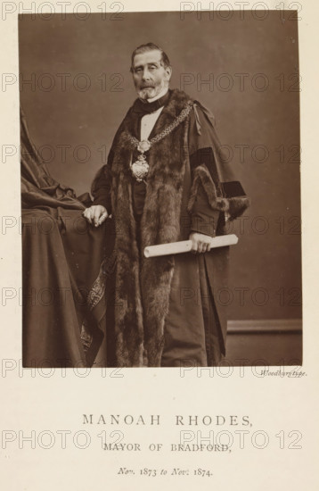 Portrait of Manoah Rhodes, Manoah Rhodes, mayor of Bradford, page, photomechanical print, inscription: 'Nov. 1873 to Nov. 1874.', photographer: Appleton & Co., Bradford (England), cliché maker: anonymous, c. 1871 - in or before 1881, paper, Woodburytype, height 116 mm x width 91 mm, historical persons (portraits and scenes from the life), A sepia portrait of an older man standing, wearing a dark formal robe trimmed with fur and a decorative chain with a large pendant around his neck, his hair combed back and a full beard and mustache; he rests one hand on a draped tablecloth and holds a rolled scroll in the other hand, with the background a plain studio backdrop and a narrow light border around the image.