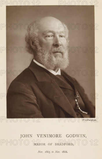 John Venimore Godwin, mayor of Bradford, Portrait of John Venimore Godwin, page, photomechanical print, inscription: 'Nov. 1865 to Nov. 1866.', photographer: Appleton & Co., Bradford (England), cliché maker: anonymous, c. 1871 - in or before 1881, paper, Woodburytype, height 117 mm x width 92 mm, Person, historical persons (portraits and scenes from the life) ((full) bust portrait), A sepia-toned portrait of an older man shown from the chest up, facing slightly to the viewer's left, with a bald head and a full curly beard and mustache, wearing a dark suit jacket over a vest and a white collar, a watch chain visible on the vest, set against a plain backdrop and framed by a light border.