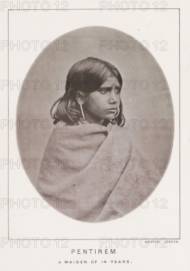 Pentirêm a maiden of 14 years, page, photomechanical print, number: 'No. 24', photographer: Bourne & Shepherd, Nilgiris, photographer: Nicholas & Curths, cliché maker: anonymous, printer (person): Autotype Printing Company, London, c. 1863 - in or before 1873, printer (person), paper, collotype, photoprint, height 121 mm x width 98 mm, adolescent, young woman, maiden, A sepia-toned oval portrait of a young person wrapped in a blanket, shown from the chest up and turned slightly to the side, with straight dark hair falling to shoulder length, large round earrings, and a neutral facial expression, set against a plain background and surrounded by a rectangular page border.