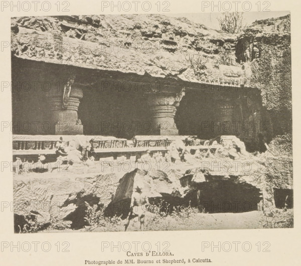 Caves d'Ellora, Exterior of an ornamented cave temple at Ellora, page, photomechanical print, inscription: 'Photographie de MM. Bourne et Shepherd, à Calcutta.', photographer: Bourne & Shepherd, Ellora, cliché maker: anonymous, c. 1875 - in or before 1884, Bourne & Shepherd, photographer, cliché maker, paper, collotype, photoprint, height 118 mm x width 153 mm, cave, grotto, temple, shrine, non-Christian religions, sculpture (relief, sculpture), A monochrome photograph showing a rock-cut facade with a dark recessed opening supported by carved columns and a carved horizontal band above, a rocky overhang with textured stone and small vegetation above the opening, rough stone foreground and scattered rocks, and a person standing near the front wearing minimal clothing.