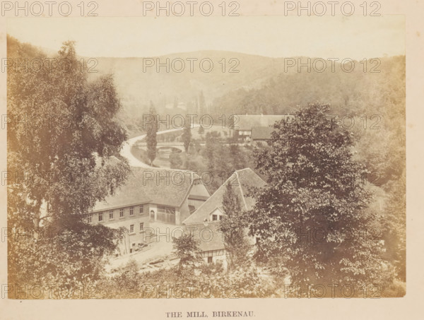 The Mill, Birkenau, View of a house on the Rhine in Birkenau, photograph, page, photographer: Francis Frith, c. 1855 - in or before 1865, Hesse, paper, albumen print, height 122 mm x width 172 mm, river, housing, A sepia-toned landscape showing a cluster of pitched-roof buildings partially obscured by large leafy trees, a winding river visible beyond the buildings with a small arched bridge crossing it, tall slender trees lining the riverbank, rolling forested hills in the background, and dense foliage filling the foreground and sides of the scene.
