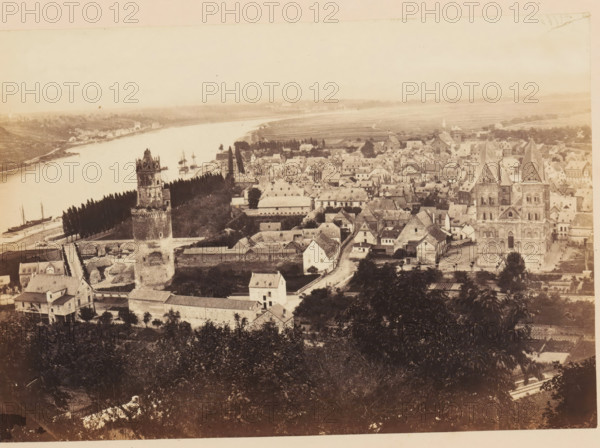 View of Andernach, Andernach, photograph, page, photographer: Francis Frith, c. 1855 - in or before 1865, Rhineland-Palatinate, paper, albumen print, height 116 mm x width 168 mm, city-view, and landscape with man-made constructions, tower, clock tower, monumental adornment, A sepia-toned aerial view of a riverside town showing a wide river curving along the left side with small sailing vessels moored near the shore, a tree-lined embankment running beside the water, a prominent stone tower with battlements near the foreground, a large church with twin spires and detailed stone façade toward the right, dense clusters of pitched-roof houses and narrow streets filling the central area, rectangular walled compounds and low buildings surrounding the tower, scattered trees and gardens among the buildings, and open fields stretching into the distant horizon under a pale sky.
